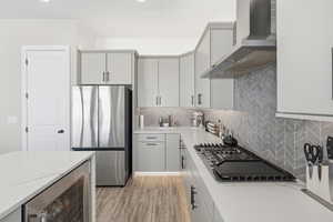 Kitchen featuring stainless steel appliances, beverage cooler, light stone countertops, and light wood-type flooring