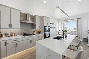 Kitchen with light wood-style floors, a breakfast bar area, hanging light fixtures, a center island with sink, and stainless steel appliances