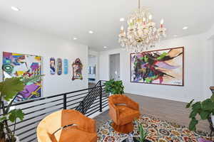 Living area with suspended lighting, wood finished floors, and an upstairs landing