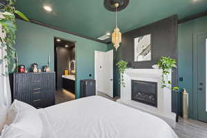 Bedroom featuring a glass covered fireplace, crown molding, recessed lighting, and connected bathroom