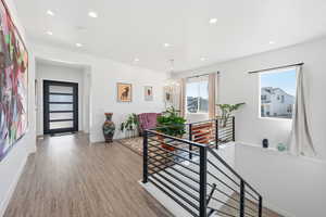 Hall with light wood finished floors, a chandelier, and an upstairs landing