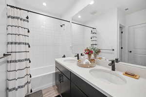 Bathroom featuring shower / tub combo, double vanity, light wood finished floors, and recessed lighting