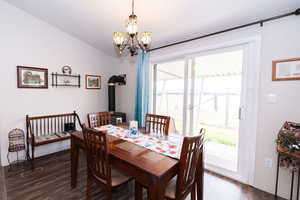 Dining space featuring dark wood-style floors, lofted ceiling, and suspended lighting