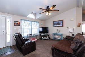 Living room featuring ceiling fan, vaulted ceiling, and carpet