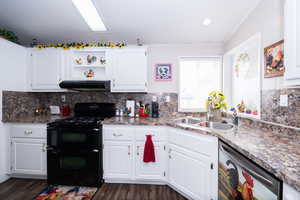 Kitchen with black gas stove, dishwasher, open shelves, white cabinets, and backsplash