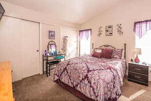 Bedroom featuring dark carpet, a closet, and vaulted ceiling