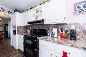 Kitchen featuring double oven range, white cabinetry, open shelves, and backsplash