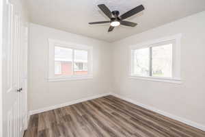 Empty room featuring dark wood-style floors, a textured ceiling, and a ceiling fan