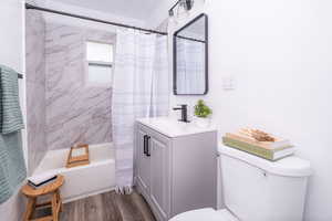Full bathroom with shower / tub combo with curtain, vanity, and dark wood-type flooring