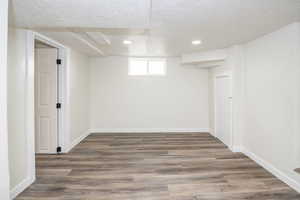 Basement with a textured ceiling, wood finished floors, and recessed lighting