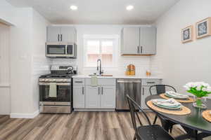 Kitchen featuring gray cabinets, stainless steel appliances, dark wood-style floors, a textured ceiling, and recessed lighting