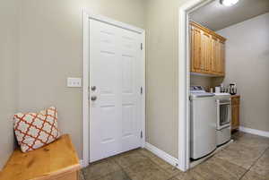 Laundry area featuring cabinet space, washer and clothes dryer, and light tile patterned floors