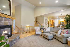 Living area featuring a stone fireplace, lofted ceiling, recessed lighting, and light wood finished floors