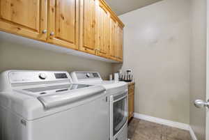 Laundry room with cabinet space, washer and dryer, and light tile patterned floors
