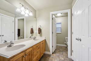 Full bath featuring double vanity, stone finish floors, and a textured ceiling