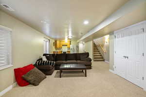 Living room with stairway and light carpet