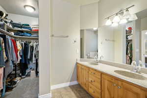 Primary Bathroom featuring a spacious closet, double vanity, and a textured ceiling