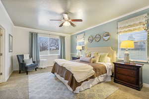 Carpeted primary bedroom featuring ceiling fan, a textured ceiling, and ornamental molding