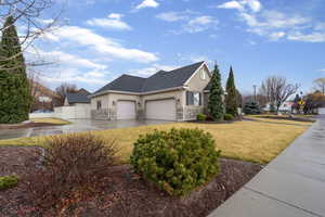 View of home's exterior with stucco siding, driveway, a 3 car garage, stone siding, and a gate