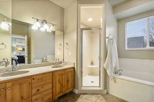 Primary En Suite Bathroom featuring double vanity, a shower stall, a bath, and light tile patterned floors