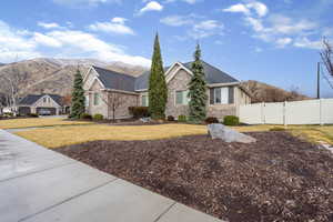 View of front facade with stone siding, a mountain view, a gate, and roof with shingles
