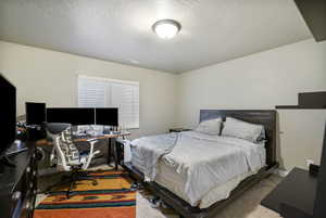 Bedroom with an office area, a textured ceiling, and carpet flooring