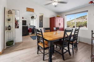 Dining room with light wood finished floors, ceiling fan, and lofted ceiling