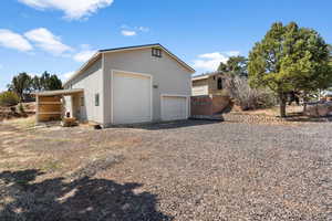 View of side of property with an outdoor structure, a detached garage, and gravel driveway