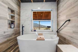 Bathroom with a freestanding tub, tile walls, and a mountain view