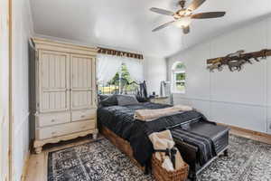 Bedroom with wood finished floors, ceiling fan, ornamental molding, and a decorative wall