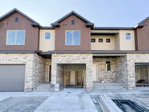 View of front featuring stone, siding, garage, and driveway