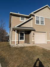 View of front of home with a front yard, a garage, covered porch, and driveway