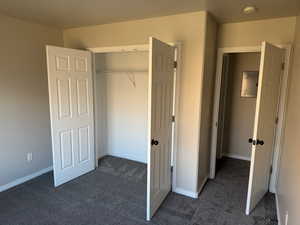 Unfurnished bedroom featuring dark carpet, a closet, and electric panel