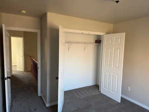 Unfurnished bedroom with dark carpet and a closet