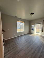 Spare room featuring dark wood-style floors and baseboards