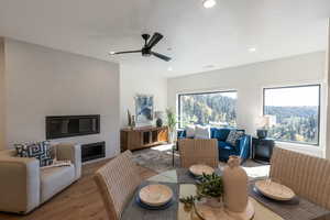Dining room with wood finished floors, a ceiling fan, a glass covered fireplace, and recessed lighting