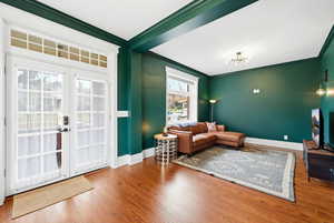 Entrance foyer with ornamental molding, wood-type flooring, and french doors