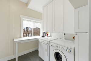 Laundry area with cabinet space, dark tile patterned flooring, and independent washer and dryer