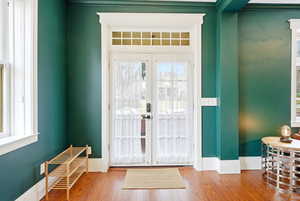 Foyer with french doors, wood finished floors, and crown molding