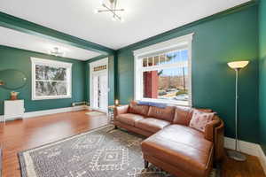 Living area with wood finished floors, hanging lights, and crown molding