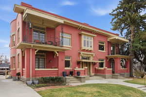 View of front of home featuring a balcony, brick siding, and a front lawn
