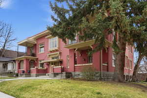 View of front of property featuring a balcony, brick siding, and a front yard