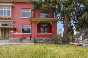 View of front of home featuring a front lawn, a balcony, and brick siding