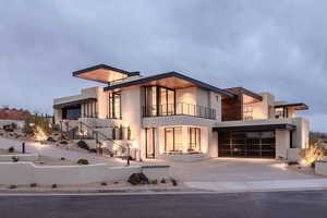 Contemporary home featuring a balcony, driveway, and stucco siding