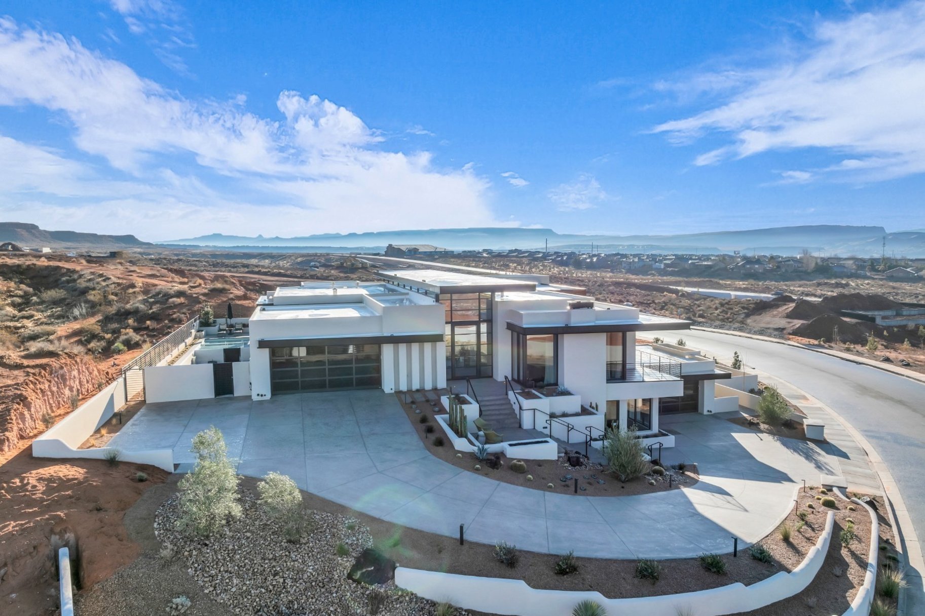 View of front of property with a mountain view, a fenced backyard, concrete driveway, and stucco siding