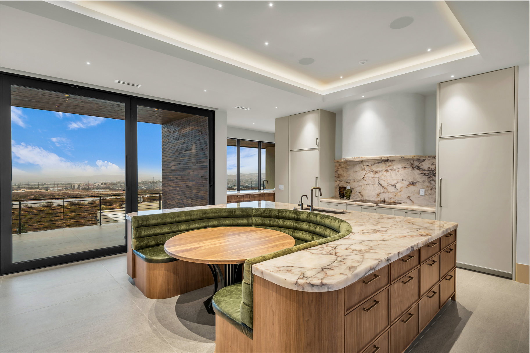 Kitchen with modern cabinets, expansive windows, a kitchen island with sink, light stone countertops, and tasteful backsplash