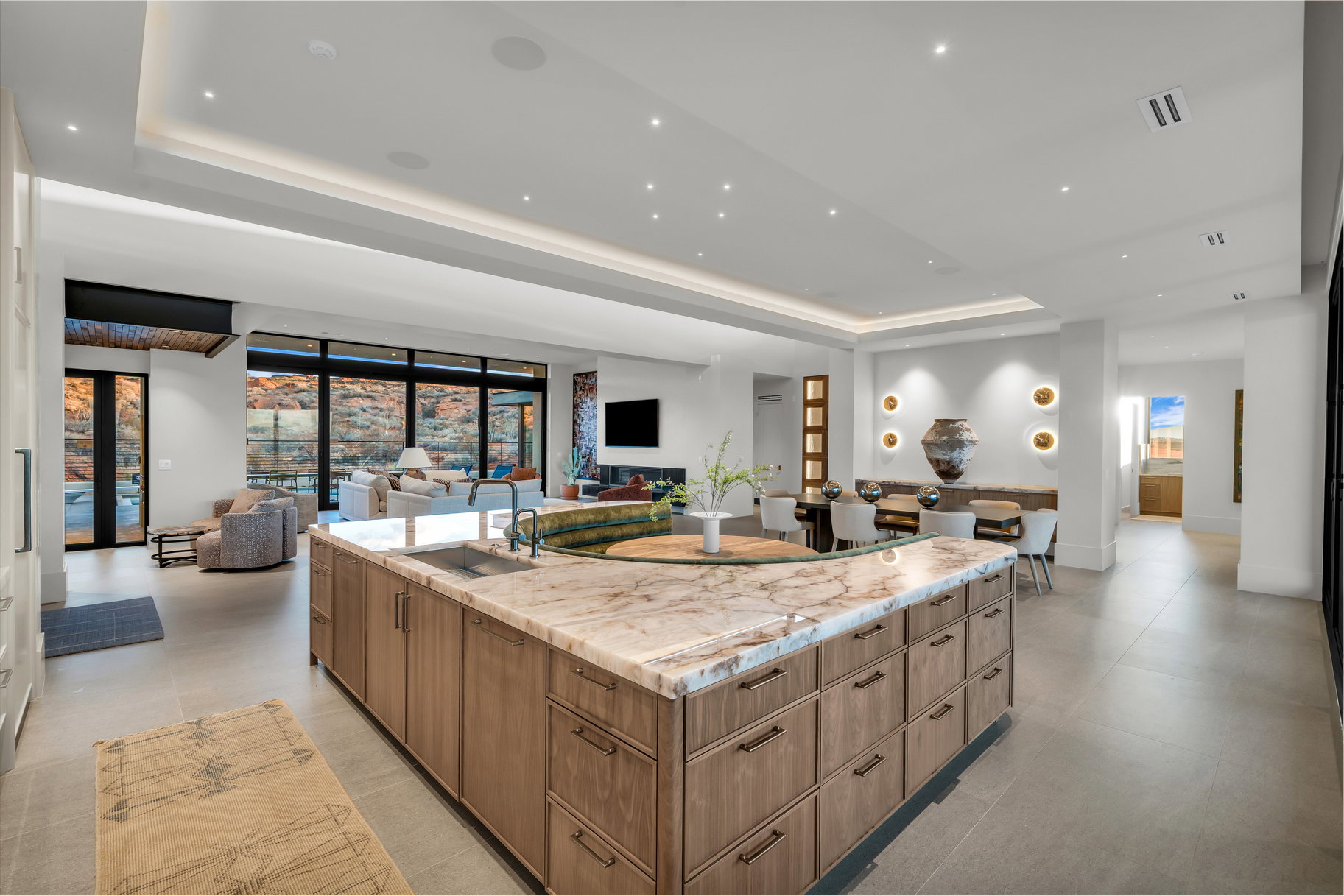 Kitchen featuring plenty of natural light, open floor plan, a large island with sink, light stone countertops, and a tray ceiling