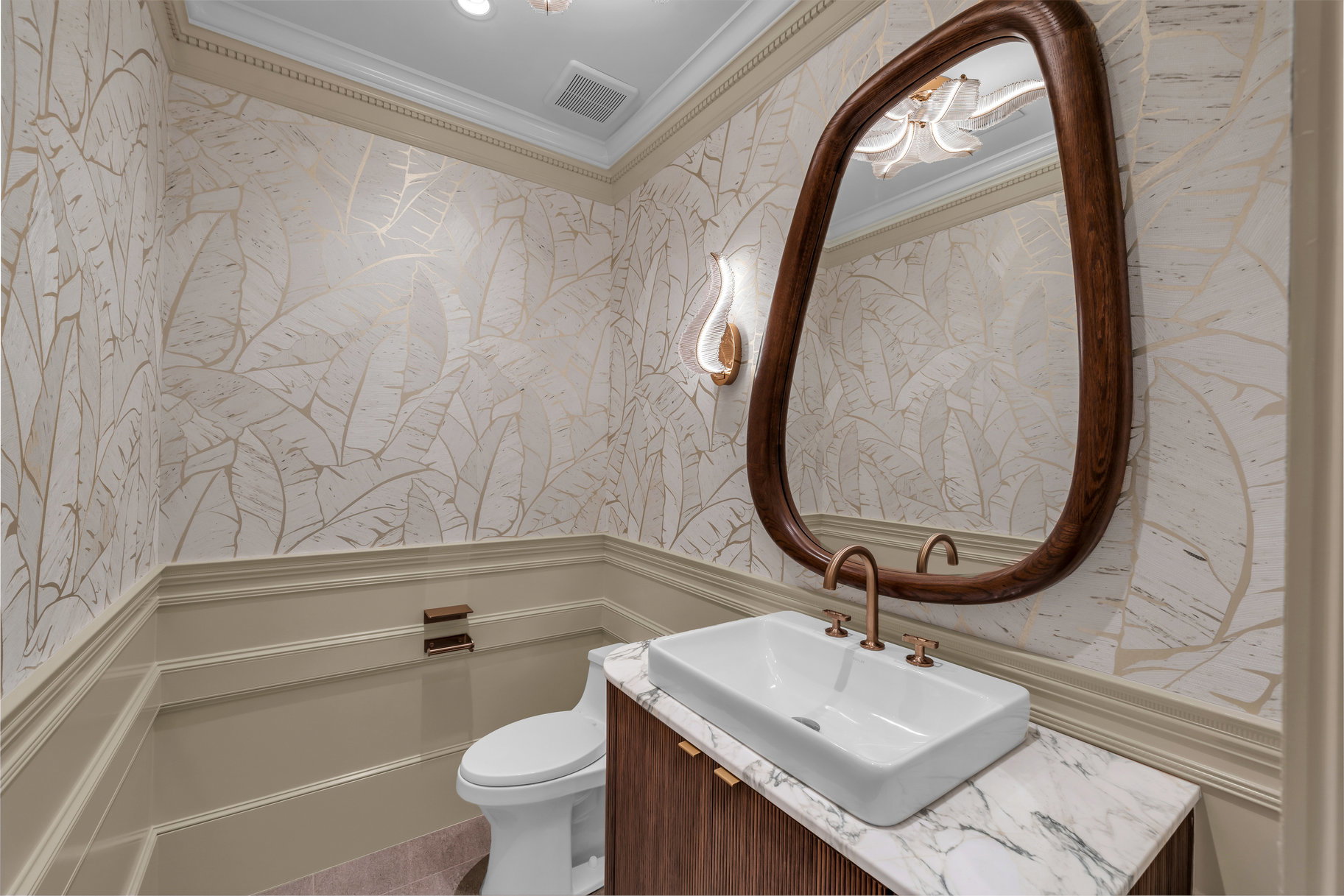 Half bath with wallpapered walls, a wainscoted wall, ornamental molding, vanity, and a decorative wall