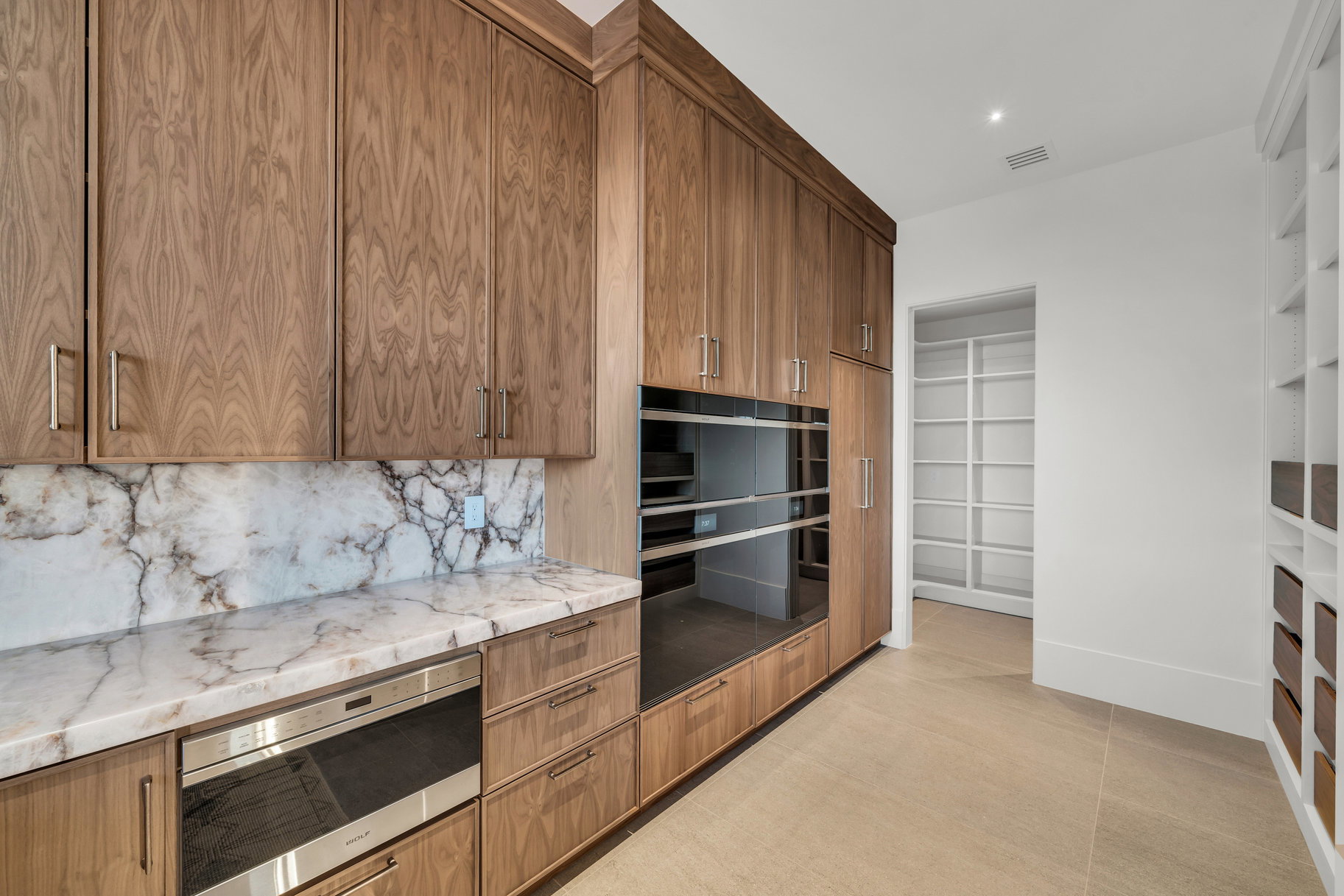 Kitchen featuring wood finish cabinets, light stone counters, stainless steel microwave, decorative backsplash, and modern cabinets
