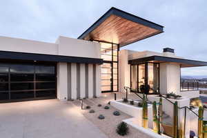 View of exterior entry with concrete driveway, stucco siding, and an attached garage
